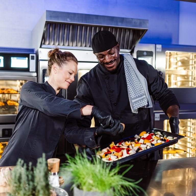 Professionelle Köche bereiten bunte Speisen in einer Großküche mit Kombidämpfer vor